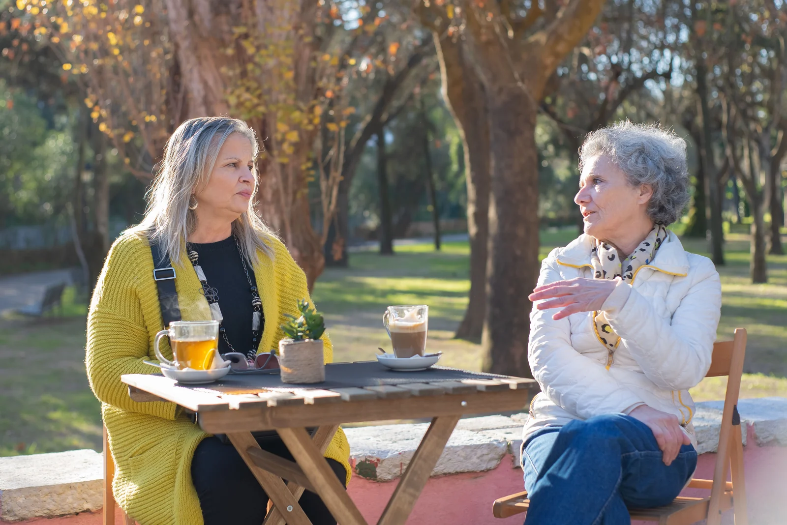 Two women sharing conversation over tea outdoors.